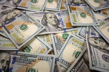 Close-up stack of hundred dollar bills isolated on black background.