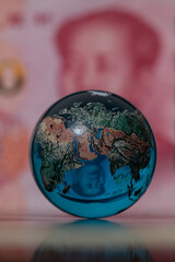 Glass globe in front of a 100 Chinese yuan banknote