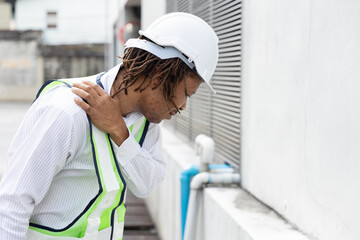 Overworked and injured Male African engineer worker having shoulder pain or injury, work related injury or accident concept