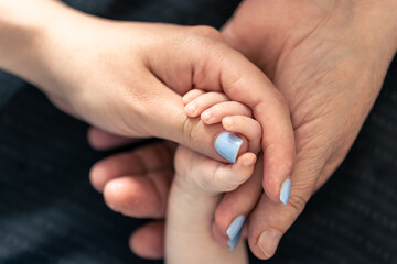 Close-up, hands of a baby, mother and grandmother.