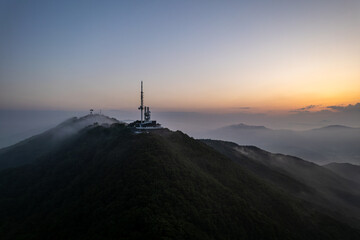 Aerial view of mountain peak against sky surrounded by fog during sunrise