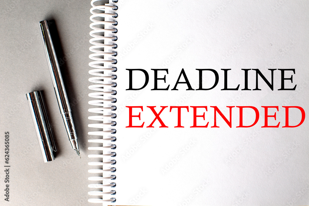 Poster deadline extended text on a notebook with pen on grey background