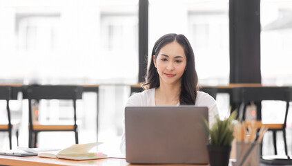 Obraz na płótnie Canvas Young asian woman using laptop computer for business studying, watch online virtual webinar training meeting, video call. Focused asian woman or Latin business woman work in office, copy space. 