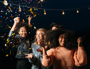Happy and laughing females dancing at night under confetti