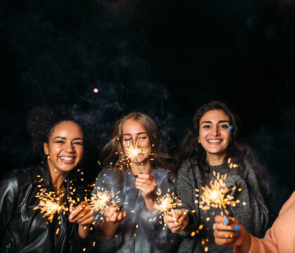 Three Happy Females With Sparklers. Group Of Diverse Female Friends At Night.