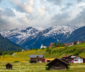 Summer Alpine mountain country view with grassy meadow and road to village (Austria)