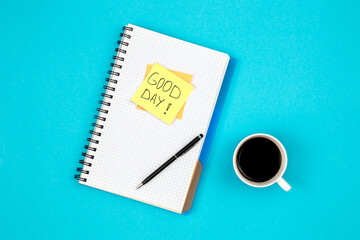 Paper sticky with the inscription Good day, a notepad and a cup of coffee.