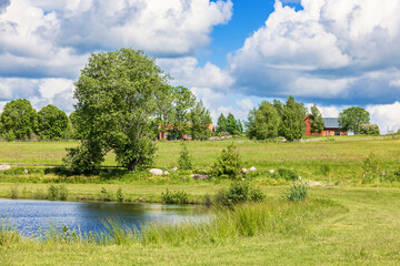 Fototapeta na wymiar Lake in a rural landscape with farm on a hill