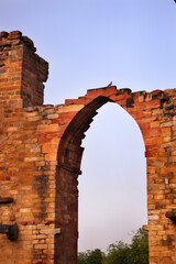 Carved Stone view of ruined walls and arches with Qutub Minar in background at Qutub Complex known as Unesco World Heritage Site, New Delhi, India, Asia.