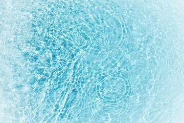 Blue water with ripples on the surface. Defocus blurred transparent blue colored clear calm water surface texture with splashes and bubbles. Water waves with shining pattern texture background.