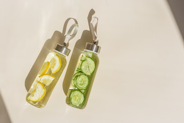 Water drink detox with  lemon and cucumber in glass bottle at sunlight on beige background....