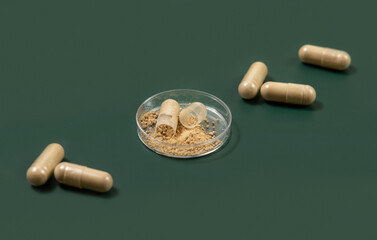 Taking dietary supplements with capsules. One capsule Opened in a jar on green