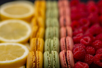 macaroons of different colors with raspberries and lemon