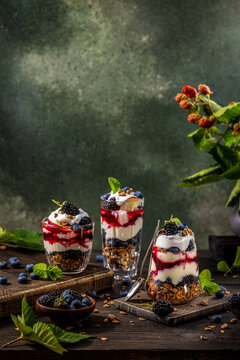 Homemade granola with greek yogurt, berries jam and fresh blackberries and blueberries in glasses