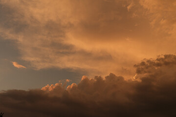 Orange yellow red purple black sky with clouds. Dark dramatic ominous clouds background. Storm, hurricane, lightning, after rain, cloudiness or armagenon in the sky, apocalypse, concept of horror, 