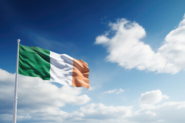 Irish flag flying in the wind on a flagpole against a blue sky with clouds. Green white yellow flag of the Ireland wallpaper.  