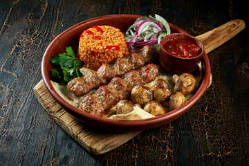 Lamb Lyulya kebab with bulgur and grilled mushrooms in a clay plate. Turkish food