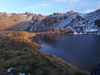 The sunrise's golden light over the snowy mountains and the lake of New Zealand's track