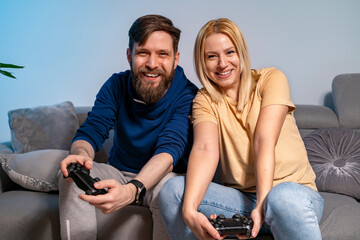 Happy young Caucasian couple playing video gam console at home