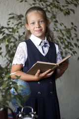 Primary schoolgirl, in school uniform, with a book.