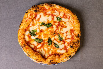 Pizza Margherita tradizionale napoletana con sugo di pomodoro, mozzarella e basilico fresco servita in una pizzeria elegante e fotografata dall'alto