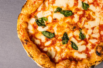 Pizza Margherita tradizionale napoletana con sugo di pomodoro, mozzarella e basilico fresco servita in una pizzeria elegante e fotografata dall'alto