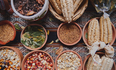 Various dried spices, andean cereals and grains in small bowls and raw herbs, pachamama payment,...