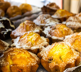 Cupcakes on display. Freshly baked cupcakes with powdered sugar behind a glass showcase in a cafe.