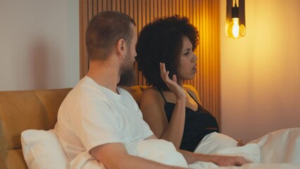 Angry interracial couple arguing in bed, stressed husband walking away, breakup