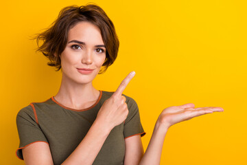 Portrait of nice woman with short hairdo wear khaki top directing at palm present object empty...