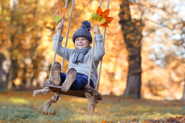 lachender Junge auf einer Schaukel im Herbst