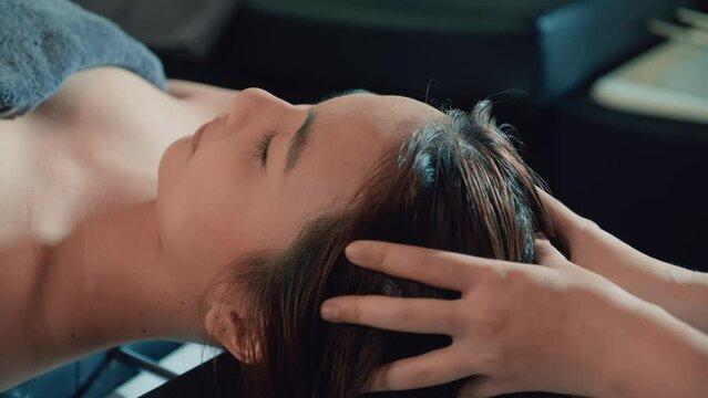 Close up shot of hairdresser massaging head of female client at spa salon