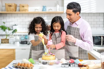 Fotobehang Portrait of enjoy happy love asian family father and little toddler asian girl daughter child having fun cooking together with dough for homemade bake cookie and cake ingredient on table in kitchen © Art_Photo