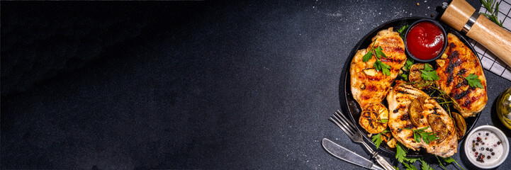 Grilled roasted chicken, turkey fillet. Spicy bbq fried white meat boneless fillet with garlic, rosemary, lemon and ketchup sauce, on black concrete table background top view copy space