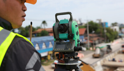 Civil or survey technician working at a new road construction site with a walkie-talkie and survey...