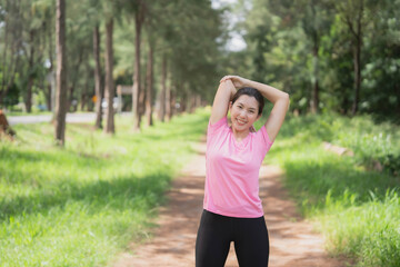 Obraz na płótnie Canvas Asian woman wearing pink gym clothes Camlang warm up and stretch before running at the park.