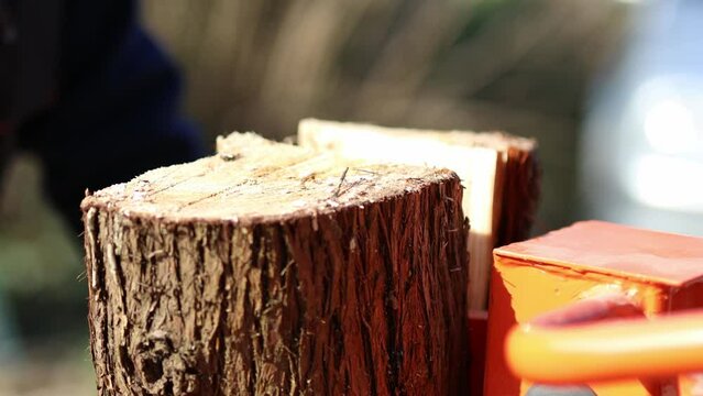 Hydraulic wood splitter cutting wood on a sunny day. 4K Video