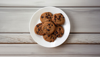 chocolate chip cookies on a pink plate. White wooden background. From above.