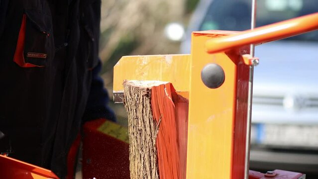 Hydraulic wood splitter cutting wood on a sunny day. 4K Video