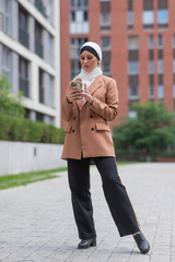 Young woman in hijab using smartphone outdoors. 