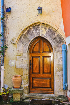 Front view of, a wood front door with limestone, arched, decorative entry way of a 1500's building