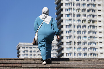 Muslim woman in hijab walking on a city street in summer