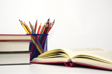 Crayon or colored pencils in box and the book placed in the blurred background. Knowledge and education concept.