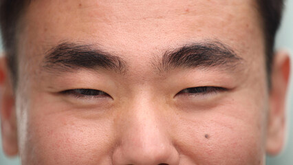Obraz premium eyes of a young happy asian man looking into the camera lens.
