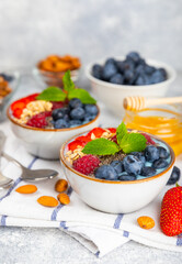 Granola bowl with yogurt and fresh almonds, blueberries, raspberries,peach and strawberries on a marble kitchen table.Acai and spirulina bowl.Healthy breakfast concept.copy space.Place for text.