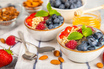 Granola bowl with yogurt and fresh almonds, blueberries, raspberries,peach and strawberries on a marble kitchen table.Acai and spirulina bowl.Healthy breakfast concept.copy space.Place for text.