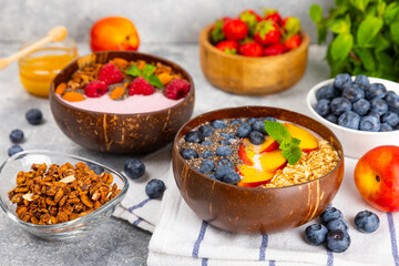 Granola bowl with yogurt and fresh almonds, blueberries, raspberries,peach and strawberries on a marble kitchen table.Acai and spirulina bowl.Healthy breakfast concept.copy space.Place for text.