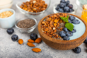Granola bowl with yogurt and fresh almonds, blueberries, raspberries,peach and strawberries on a marble kitchen table.Acai and spirulina bowl.Healthy breakfast concept.copy space.Place for text.