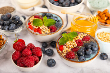 Granola bowl with yogurt and fresh almonds, blueberries, raspberries,peach and strawberries on a marble kitchen table.Acai and spirulina bowl.Healthy breakfast concept.copy space.Place for text.