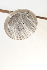 Shower head spraying water, with exposed plumbing